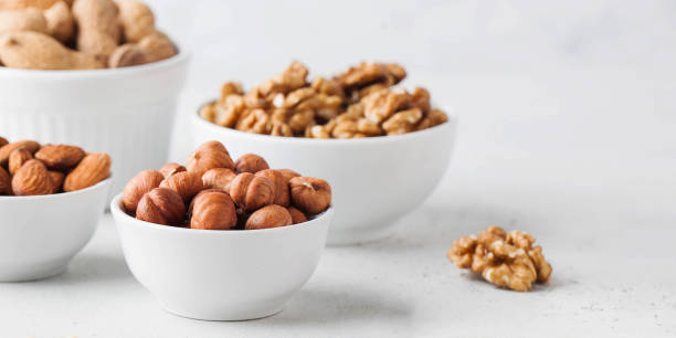 istock Hazelnuts and other nuts in white bowls on a white background. Banner 1364273767