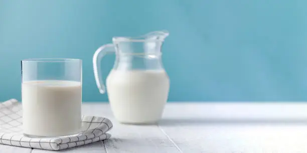 A jug and a glass of fresh milk on a blue background. High quality photo