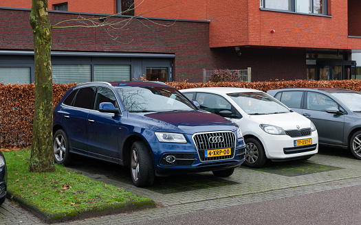 Enschede, Overijssel, Netherlands, december 15th 2021, Dutch blue 2014 Audi 1st generation Q5 station wagon (2.0 TFSI 225pk quattro Sport Edition) next to a white 2013 Skoda Citigo on a parking lot, the Q5 is a luxury crossover SUV made by German, Ingolstadt based manufacturer Audi since 2008