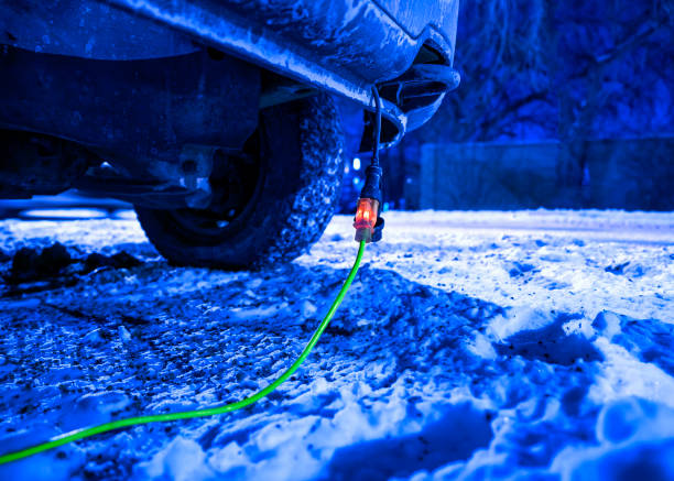 Extension cord plugged into vehicle on freezing cold night stock photo