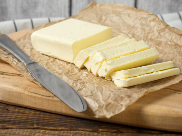 istock Fresh butter block sliced on wooden cutting board on rustic background 1364280918