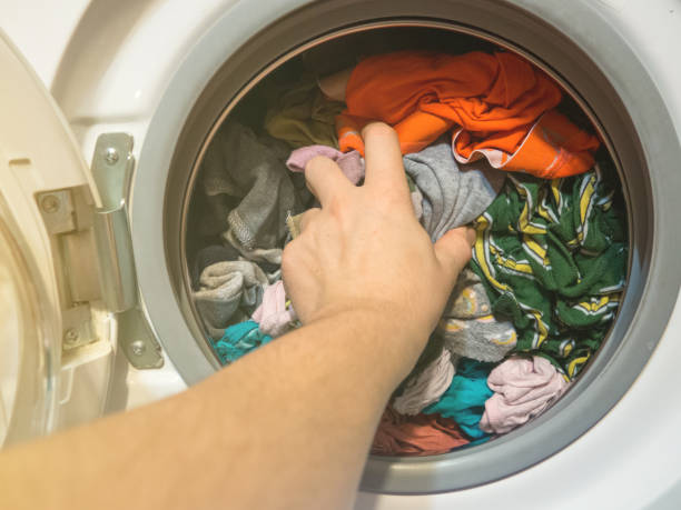 istock man puts clothes in the washing machine, close-up 1364281510