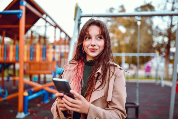 Cute Young Female Using Smartphone On Outdoor Playground