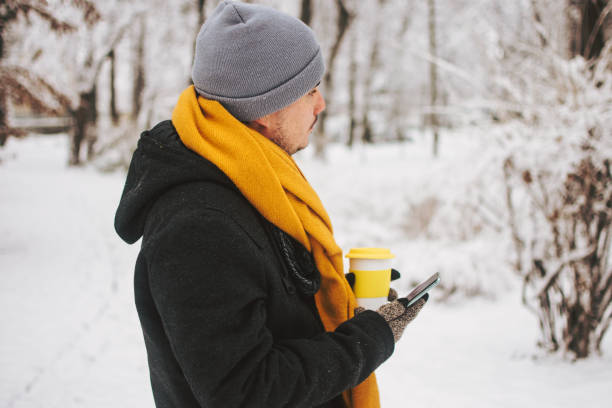 istock Young man with phone in winter park. 1364283845