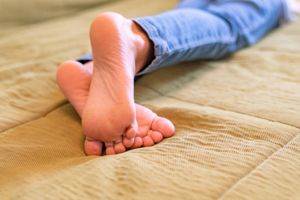 istock crossed bare kid legs on green sofa 1364291124