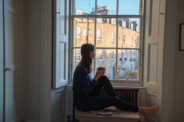 istock Young woman enjoys a tea by window at home 1364293185
