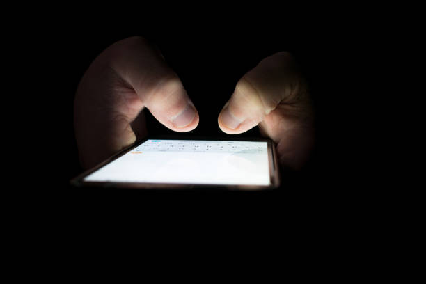 istock Fingers touching the smartphone screen with the light off 1364295411