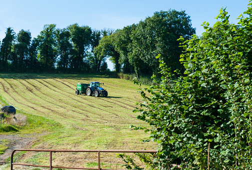 Tractor and Harvesting machine working in a green field