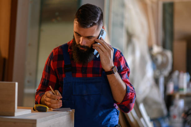 istock Young male carpenter working in workshop and using smartphone 1364297004