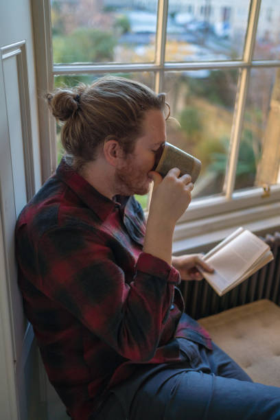 istock Young man reads book and enjoys a tea 1364297986