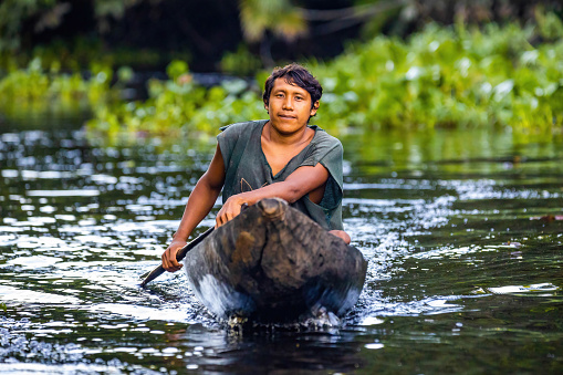 Orinoco, Venezuela - 11-23-2021: Native indigenous Orinoco fisherman swimming in traditional wooden canoe close up
