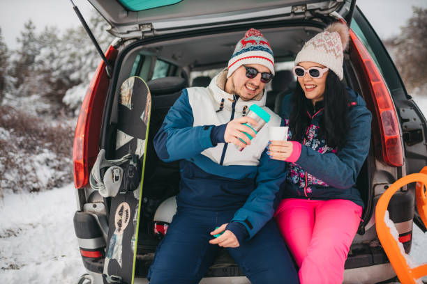 Lovely smiling couple sitting in car trunk