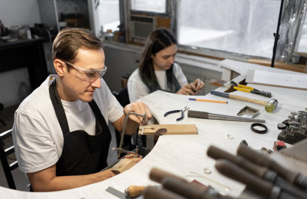 istock Happy master jewelers sitting at workbench in workshop. Processing and creation of rings. Blurred foreground tools. 1364304338