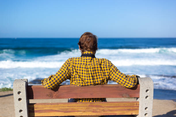 istock La Jolla, CA: Man Sitting on Bench Looking at Pacific Ocean 1364305264