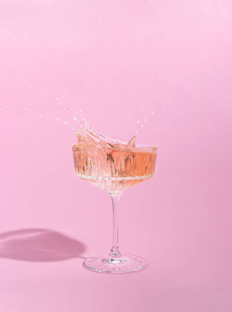 Pink champagne in a glass with splashes. Pink background. Creative minimal concept. Pink champagne in a glass with splashes. Pink background. Creative minimal concept. Copy space rose wine stock pictures, royalty-free photos & images