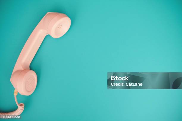 Retro Pastel Pink Rotary Telephone Receiver On A Vibrant Teal Background With Space For Copy Stock Photo - Download Image Now