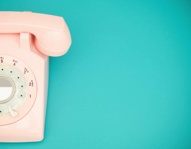 istock Retro pastel pink rotary telephone on a vibrant teal background with space for copy 1364310844
