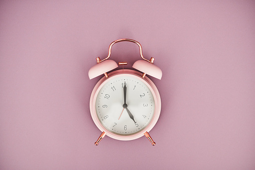 Rose pink retro alarm clock on a pink background with space for text