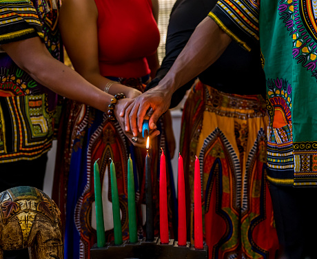 Celebración de Kwanzaa, primer plano de la familia encendiendo la vela kinara en espíritu de unidad photo