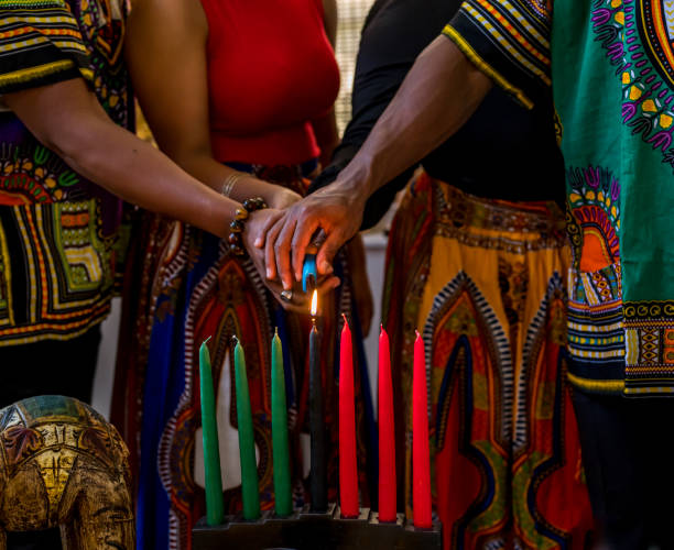 Kwanzaa celebration, close up of family lighting the kinara candle in spirit of unity stock photo