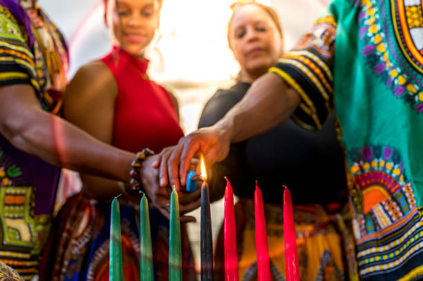 kwanzaa-feier, afroamerikanische familie, die die kinara-kerze gemeinsam zu hause im geiste der einheit anzündet - kwanzaa stock-fotos und bilder