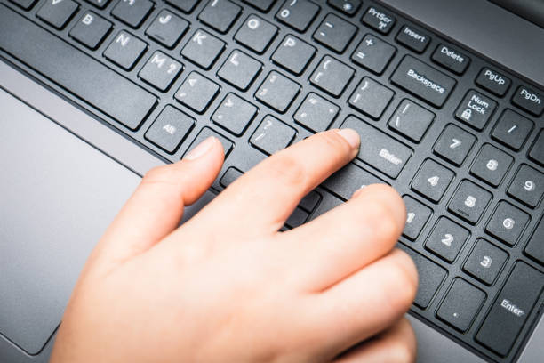 Closeup image of finger pushing button enter provide with data on the laptop computer. Press keyboard on the notebook hardware equipment concept. Above view