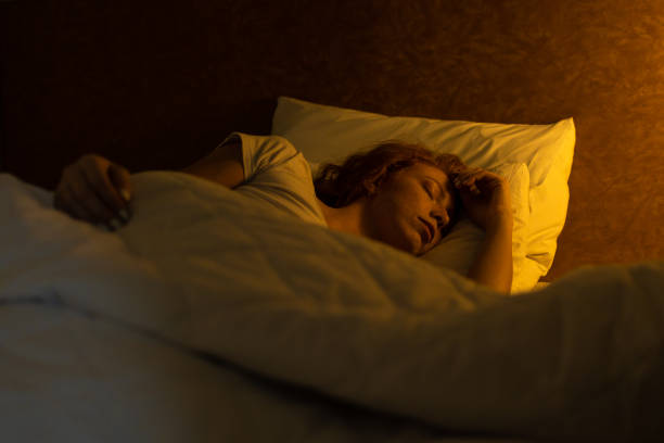 istock Young girl sleeps with her head on the pillow under a yellow light 1364314737
