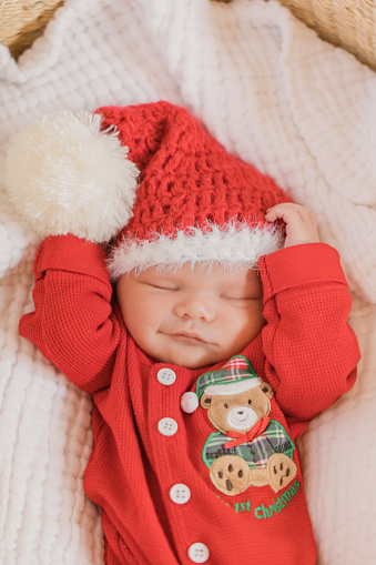 Newborn Christmas Baby Dressed in a Cozy Red Christmas Outfit Asleep Snuggly in His Moses Basket. Baby Boy only one week old.