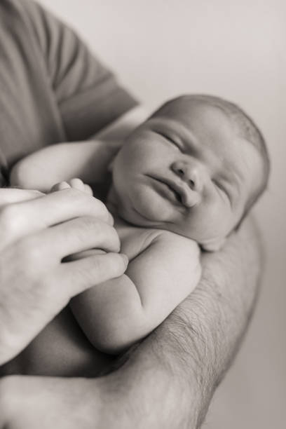 черно-белая фотография рождественского новорожденного мальчика, спящего на руках отца - human foot baby black and white newborn стоковые фото и изображения