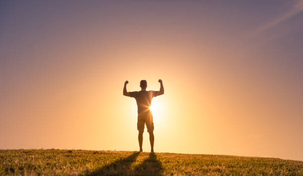 istock Strong man flexing muscles against a sunset. 1364318373