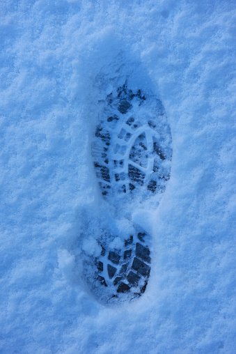 Overhead shot of marks of foot steps on snow ground in the early morning.