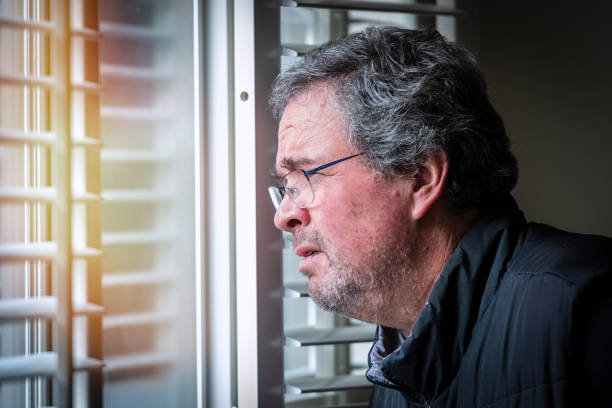 istock Serious, worried, stressed matura man looking through a window 1364319060