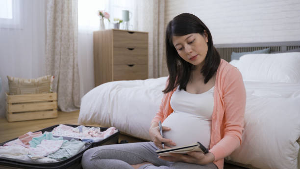 istock portrait asian mother in the third trimester is getting ready for her child’s arrival by checking all the baby supplies and marking in her notebook. 1364323658