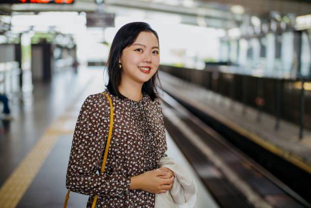 istock Asian woman waiting for train at station 1364332826