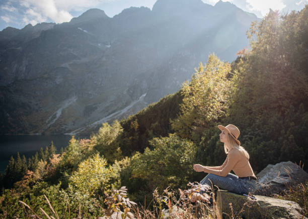 istock Young woman on a hiking trip sitting on a rock 1364333813