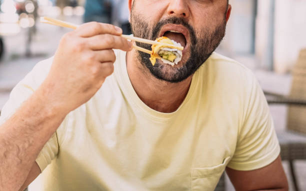 istock Man eating sushi and Japanese noodles 1364337955