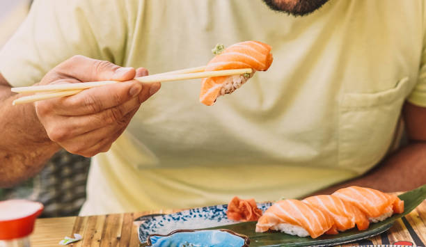 istock Man eating sushi and Japanese noodles 1364337957