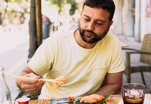 istock Man eating sushi and Japanese noodles 1364337968