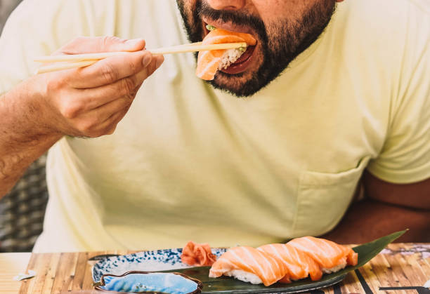 istock Man eating sushi and Japanese noodles 1364337971