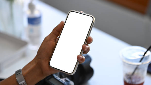 istock Close up view young woman hand holding smart phone with white empty screen. 1364338099