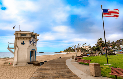 Lifeguard station and an American flag in Laguna Beach, famous tourist destination in California, Pacific Ocean in the background a on a cloudy day