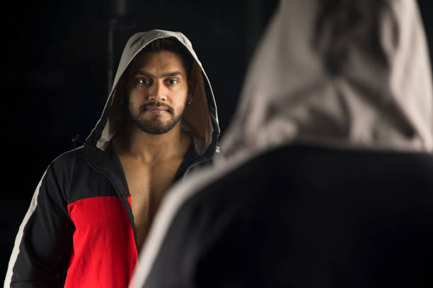 istock Man in hoodie looking into mirror at dressing room 1364344461