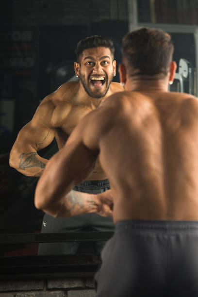 istock Muscular man flexing muscles in front of mirror 1364344686