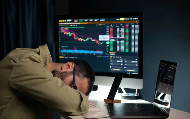 Photo of The unhappy investor who lost money in the cryptocurrency exchange, unhappy and sleepy in front of the computer