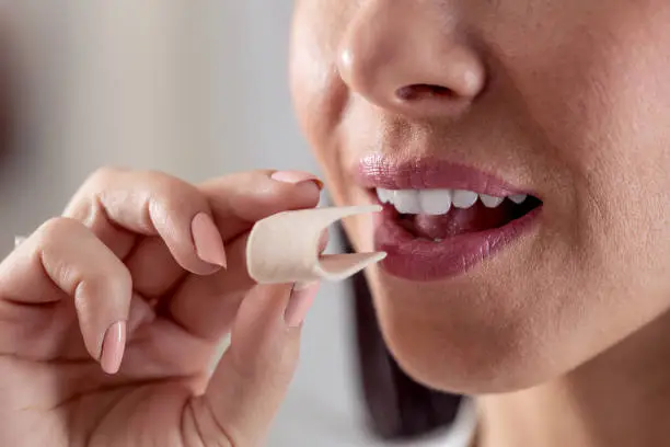 Detail of a woman putting a folded chewing gum into her mouth.