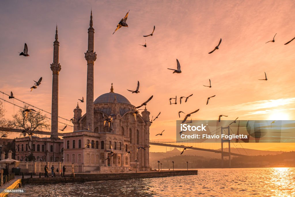The Ortaköy Mosque Ortaköy Mosque is located in Beşiktaş, Istanbul, Turkey, is situated at the waterside of the Ortaköy pier square, one of the most popular locations on the Bosphorus. This structure is symbolic of the district of Ortaköy as it has a distinctive view of the Bosphorus Strait of Istanbul and the Bosphorus Bridge here in a view with birds Istanbul Stock Photo