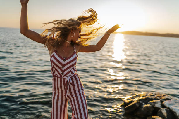 istock Beautiful young woman dancing on the beach at sunset 1364352713