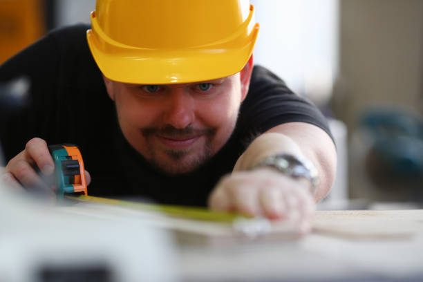 istock Man builder in helmet makes measurements with tape measure 1364354648