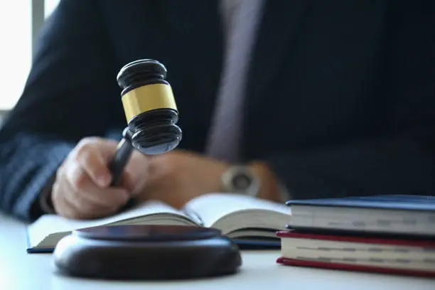 Photo of Male judge in courtroom hits with hammer