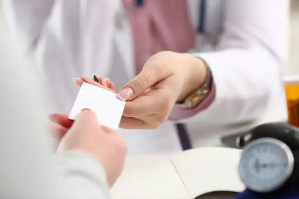Photo of Female doctor hands over white business card to patient